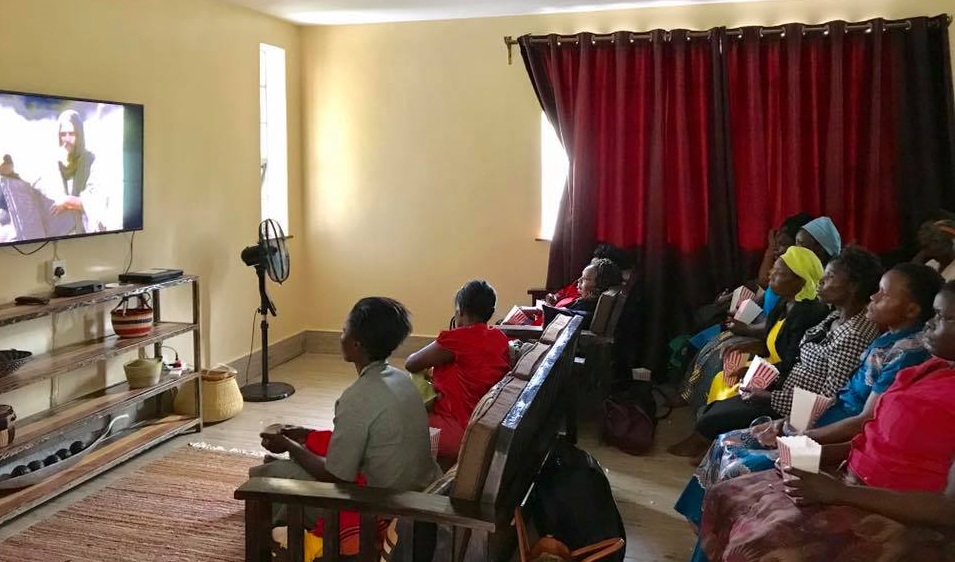 People seated in a living room watching television together.