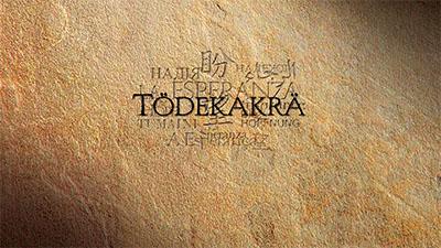 Text “TÓDBKAKRÁ” over textured brown stone background with faded script behind.