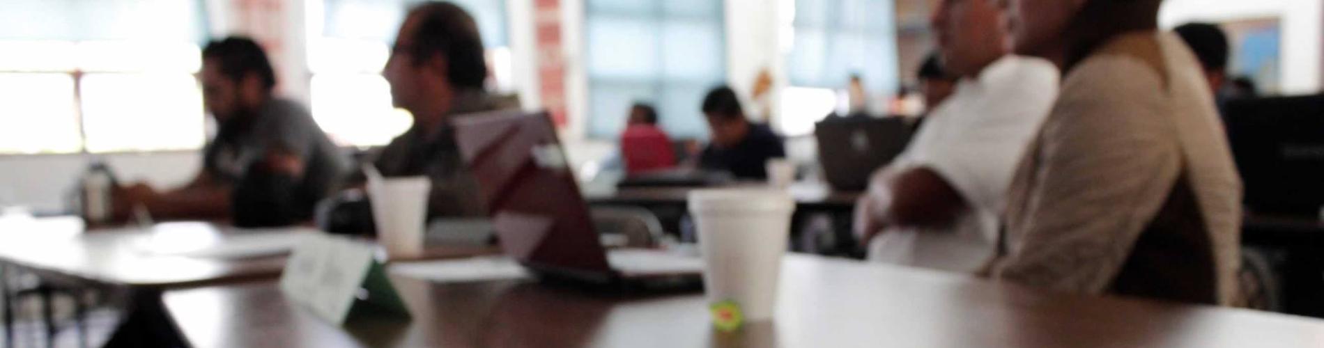 People seated at a conference table with laptops and a notepad in the foreground.