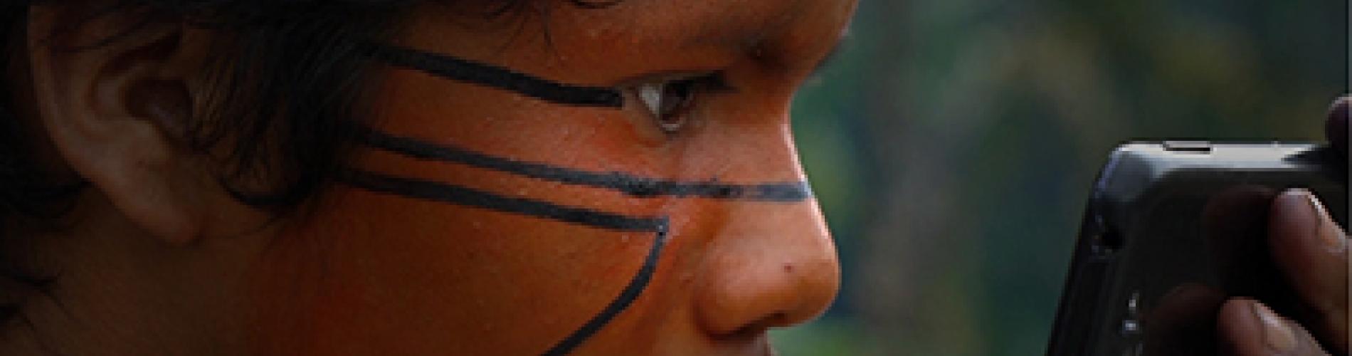 Person with face paint drawing lines while looking into a smartphone.