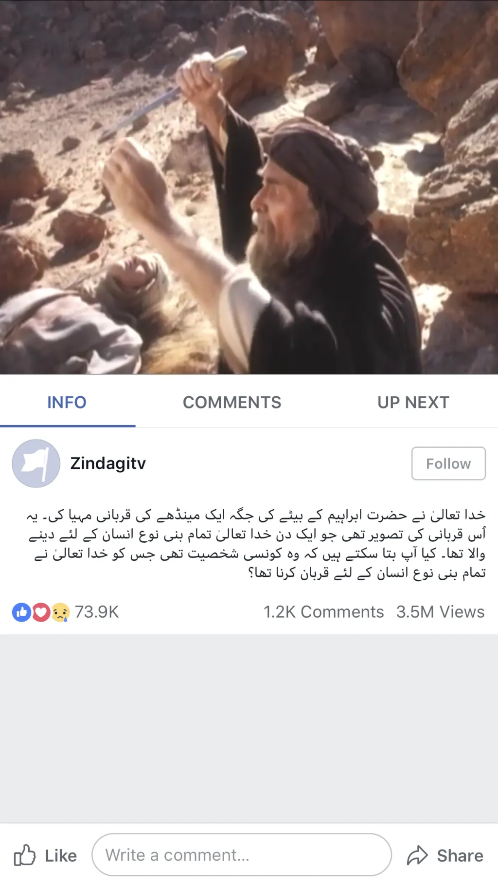 Man in traditional clothing kneeling beside another man lying on rocky ground, raising hand in distress.